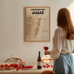 May include: A framed map of the Alsace wine region in France, with a glass of red wine and a bottle of wine on a table with red tomatoes and breadsticks.