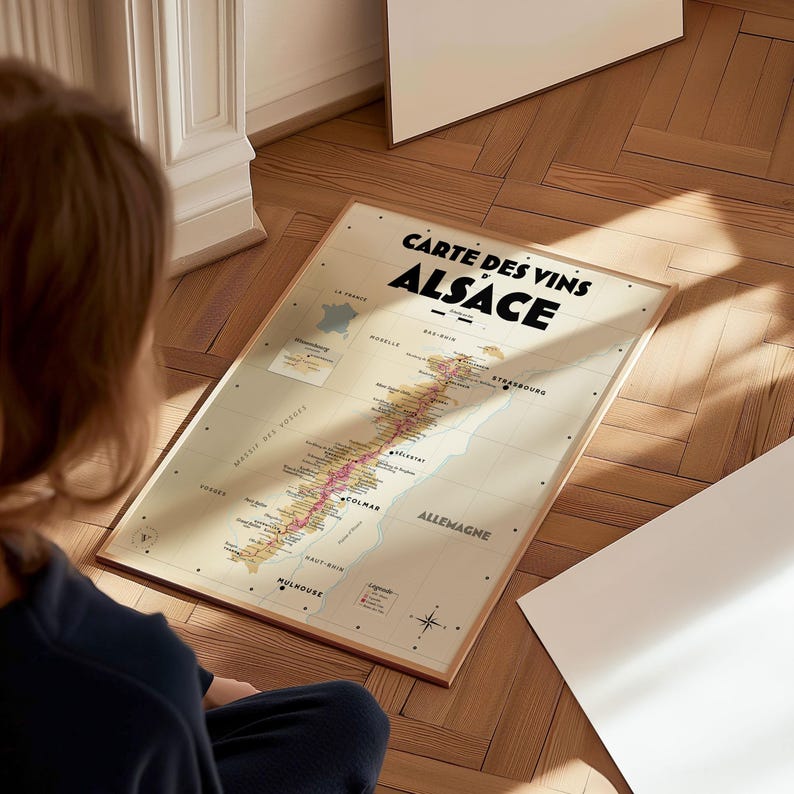 May include: A vintage-style map of the Alsace wine region in France. The map is printed on cream-colored paper and features a detailed illustration of the vineyards and towns. The title "Carte des Vins Alsace" is printed in bold black letters at the top of the map.