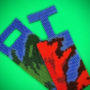 Op de afbeelding: Drie kralen sleutelhangers met verschillende patronen. De sleutelhanger links heeft een camouflagepatroon in groen, blauw en zwart. De sleutelhanger in het midden heeft een rood, blauw en zwart patroon. De sleutelhanger rechts is blauw met een witte lus.