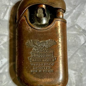 May include: Vintage bronze-colored "Fieree Tiger" windproof lighter. The lighter features an embossed eagle emblem above the text "Fieree Tiger" and "Windproof Lighter". The lighter is marked "Made in WZ-1029".