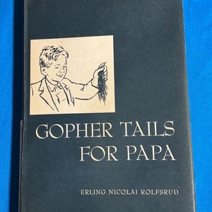 May include: A vintage book titled "Gopher Tails For Papa" by Erling Nicolai Rolfsrud. The cover is dark blue with a beige square featuring a black and white illustration of a boy holding gopher tails.