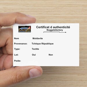 May include: A white card with black text that reads "Certificat d'authenticit&eacute; Nuggetsfactory" and lists the name, provenance, type, lot, and weight of a Moldavite tectite from the Czech Republic. The card has a small logo in the top left corner that reads "IMCa".