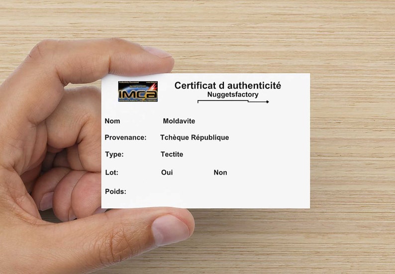 May include: A white card with black text that reads "Certificat d'authenticit&eacute; Nuggetsfactory" and lists the name, provenance, type, lot, and weight of a Moldavite tectite from the Czech Republic. The card has a small logo in the top left corner that reads "IMCa".