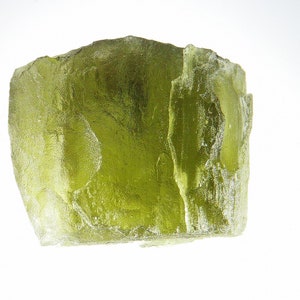 May include: A large, translucent, green, rough-hewn crystal with a slightly cloudy appearance.