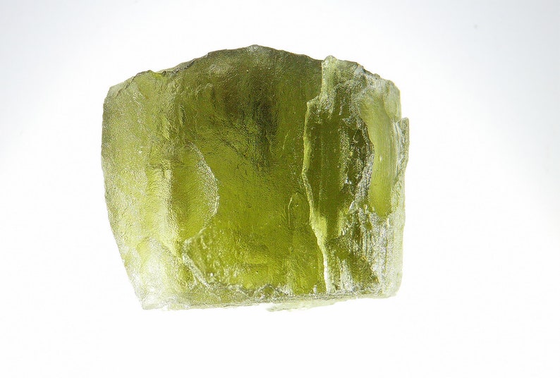 May include: A large, translucent, green, rough-hewn crystal with a slightly cloudy appearance.