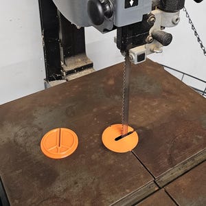 May include: A gray Porter-Cable bandsaw with a black handle and a metal table. The bandsaw has an orange blade guard and a black blade. The bandsaw is designed for cutting wood and other materials.