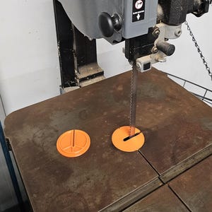 Może przedstawiać: Szara piła taśmowa Porter-Cable z czarnym uchwytem i metalowym stołem. Piła taśmowa ma pomarańczową osłonę ostrza i czarne ostrze. Piła taśmowa znajduje się w warsztacie.