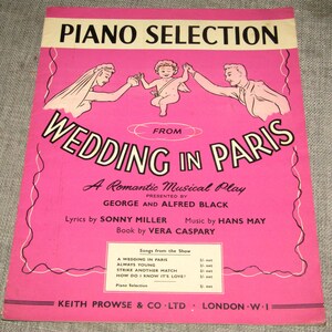 Könnte beinhalten: Ein Vintage-Notenblatt in Rosa mit dem Titel "PIANO SELECTION" für "WEDDING IN PARIS". Das Cover zeigt Illustrationen einer Braut, eines Bräutigams und eines Engels. Der Text enthält die Namen des Texters, Komponisten und Buchautors.