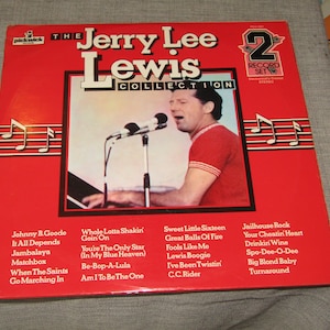 May include: A vintage vinyl record album titled "The Jerry Lee Lewis Collection" with a red cover. The album features a photo of Jerry Lee Lewis singing into a microphone. Song titles are listed on the cover.