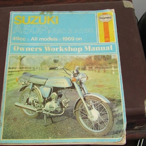 May include: A blue and white Haynes Owners Workshop Manual for a Suzuki A50P, A100 & A125 motorcycle. The manual is for all models from 1969 on and features a photo of a silver motorcycle.