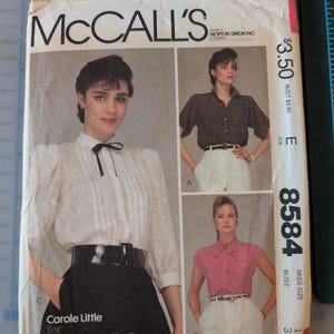 May include: Vintage McCall's sewing pattern featuring three blouse designs. The pattern cover shows women modeling the blouses. The pattern includes the text "Carole Little for Saint-Tropez West" and the pattern number 8584.