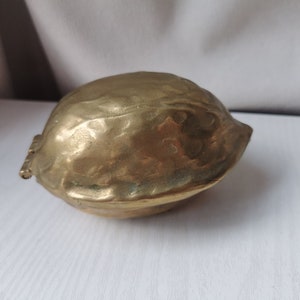 Peut inclure: Un casse-noisette en laiton en forme de noix. Le casse-noisette est fermé et présente une surface texturée détaillée.