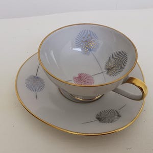Peut inclure: Service à thé blanc avec bordure dorée et motif floral bleu, rose et gris. La tasse a une anse dorée et la soucoupe un bord doré assorti. Un service à thé délicat et élégant.
