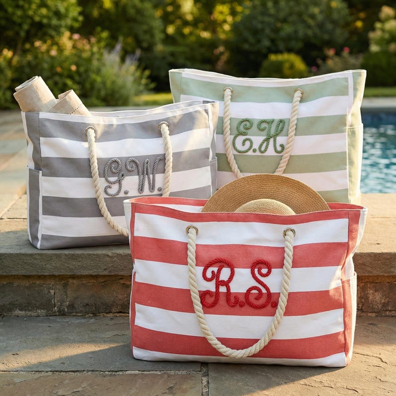 Peut inclure: Trois sacs fourre-tout &agrave; rayures grises, vertes et rouges, chacun avec des poign&eacute;es en corde et des initiales brod&eacute;es. Les sacs sont remplis d'articles, dont un chapeau de paille. Parfait pour la plage ou la piscine.