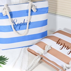 May include: Two striped tote bags with rope handles. One is blue and white, with the name "Sophia" in cursive. The other is brown and white, with "Hailey" in cursive. These bags are designed for carrying items, ideal for the beach or shopping.