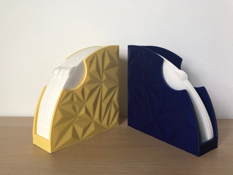 May include: Two coffee filter holders, one yellow and one blue, with a geometric design. The holders are made of plastic and have a slot for holding coffee filters.