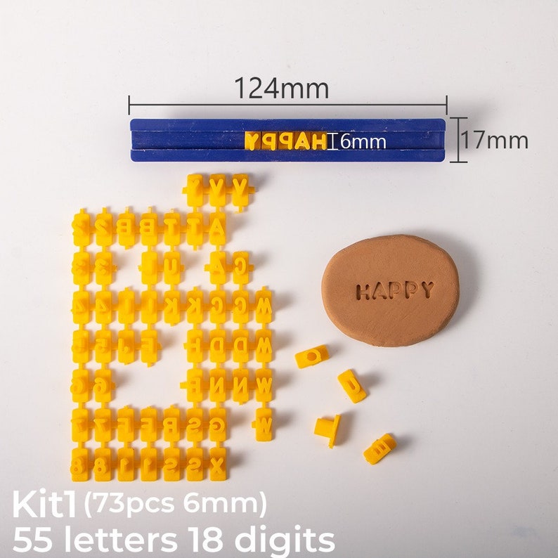 May include: A set of 73 yellow plastic alphabet stamps, including 55 letters and 18 numbers, in a blue plastic case. The stamps are 6 mm in size and can be used to create custom messages on clay, dough, or other materials. The case is 12.4 cm long and 1.7 cm wide. The text "HAPPY" is stamped on a brown clay surface.