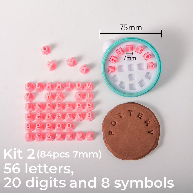 May include: A set of 84 pink alphabet and number stamps in a turquoise plastic container. The stamps are 7 mm in size and include 56 letters, 20 digits, and 8 symbols. The container is 75 mm in diameter. The text "Kit 2 (84pcs 7mm)" is visible below the stamps. The text "56 letters, 20 digits and 8 symbols" is visible below the container.