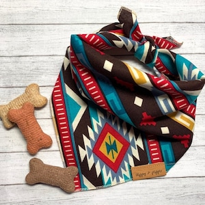 Könnte beinhalten: Ein braunes, türkisfarbenes, rotes und gelbes gemustertes Bandana mit einem abgesteppten Rand. Das Bandana ist zu einem Knoten gebunden und hat ein kleines Leder-Etikett mit der Aufschrift "Shippy & Pippy".