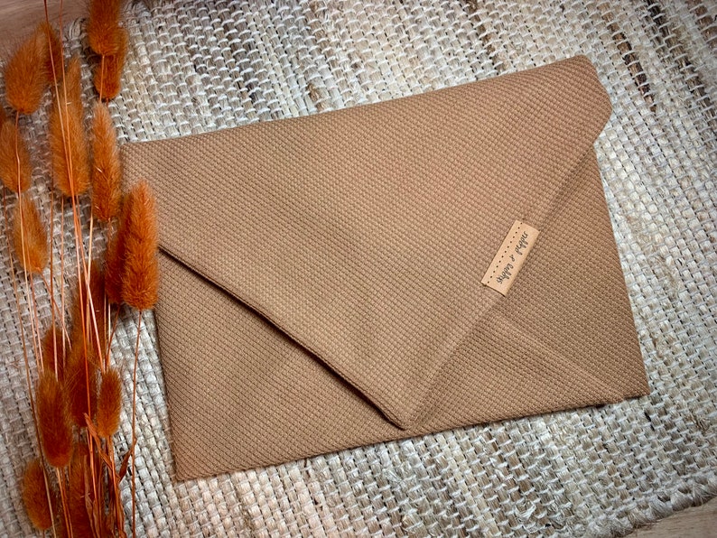 May include: A brown envelope clutch with a small leather tag that says "Super & Pepper".