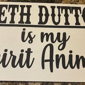 Może przedstawiać: Biały znak z czarnym tekstem, na którym napisano "Beth Dutton jest moim zwierzęciem duchowym".