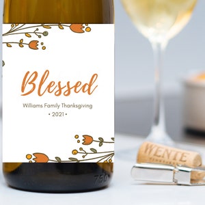 May include: A white wine bottle label with a floral design and the text "Blessed" in orange. The label also includes the text "Williams Family Thanksgiving - 2021 -."