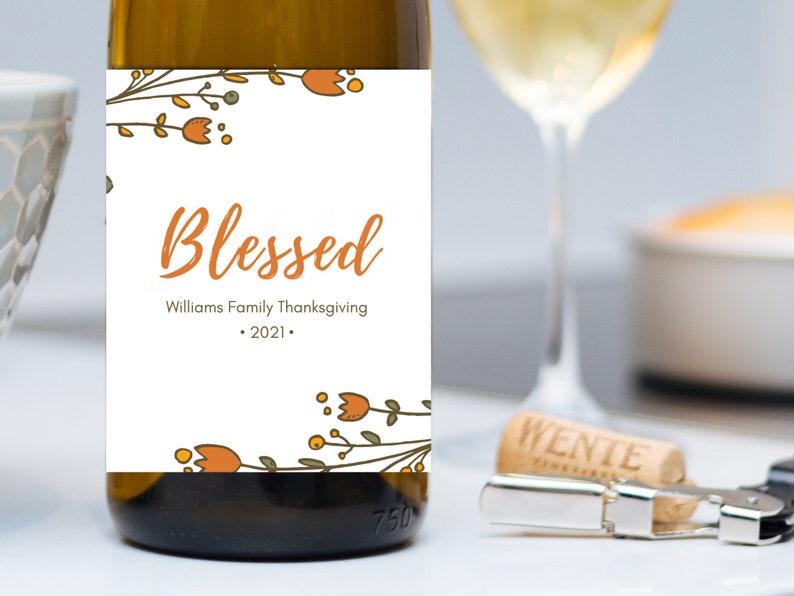 May include: A white wine bottle label with a floral design and the text "Blessed" in orange. The label also includes the text "Williams Family Thanksgiving - 2021 -."