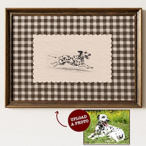 May include: A framed wall art piece featuring a brown and white gingham background with a central scalloped-edge cream-coloured paper displaying a black and white sketch of a running Dalmatian dog, plus a small inset photo with the text UPLOAD A PHOTO.