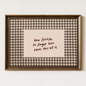 May include: Framed artwork with a brown gingham pattern background and a scalloped-edge paper insert. The insert features handwritten text in dark brown that reads, "how foolish to forget how rare this all is."