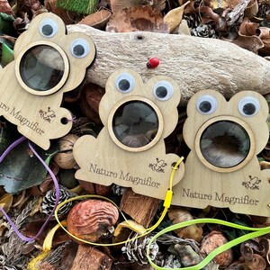 May include: Three wooden frog-shaped magnifying glasses with googly eyes and a string attached. Each magnifier has the text "Nature Magnifier" engraved on it.