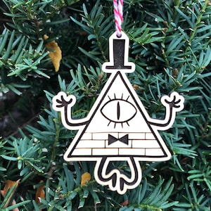 May include: A wooden Christmas ornament shaped like the character Bill Cipher from the animated series Gravity Falls. The ornament is painted in black and white and features Bill Cipher's signature eye, bow tie, and top hat.