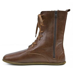 May include: Brown leather ankle boots with a lace-up front and a side zipper. The boots have a flat sole.