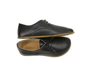 May include: A pair of black leather lace-up shoes with a brown sole. The shoes are stacked on top of each other.