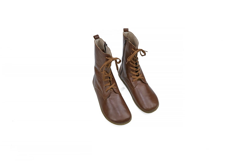 May include: A pair of brown leather ankle boots with laces. The boots have a rounded toe and a low heel.