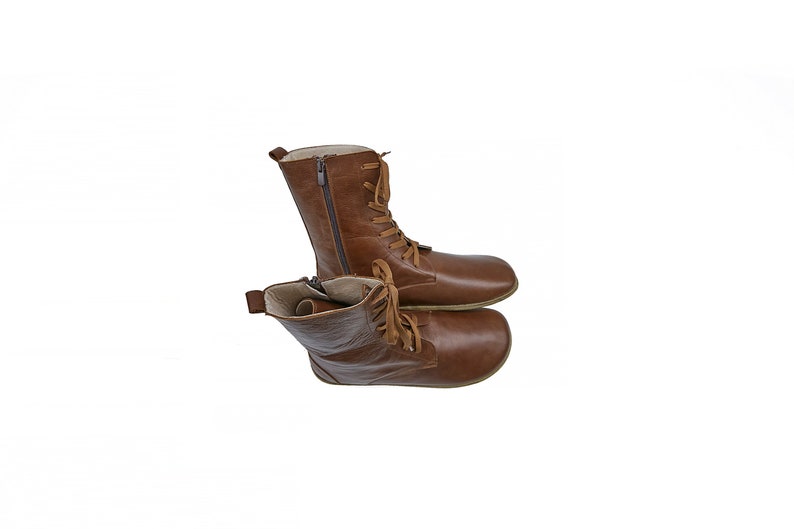 May include: A pair of brown leather boots with laces and a zipper on the side. The boots are stacked on top of each other.
