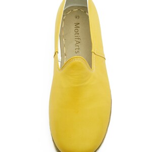 Puede incluir: Un par de zapatos de cuero amarillo de vestir sin cordones con interior blanco y el texto "MotifArts" impreso en la plantilla.