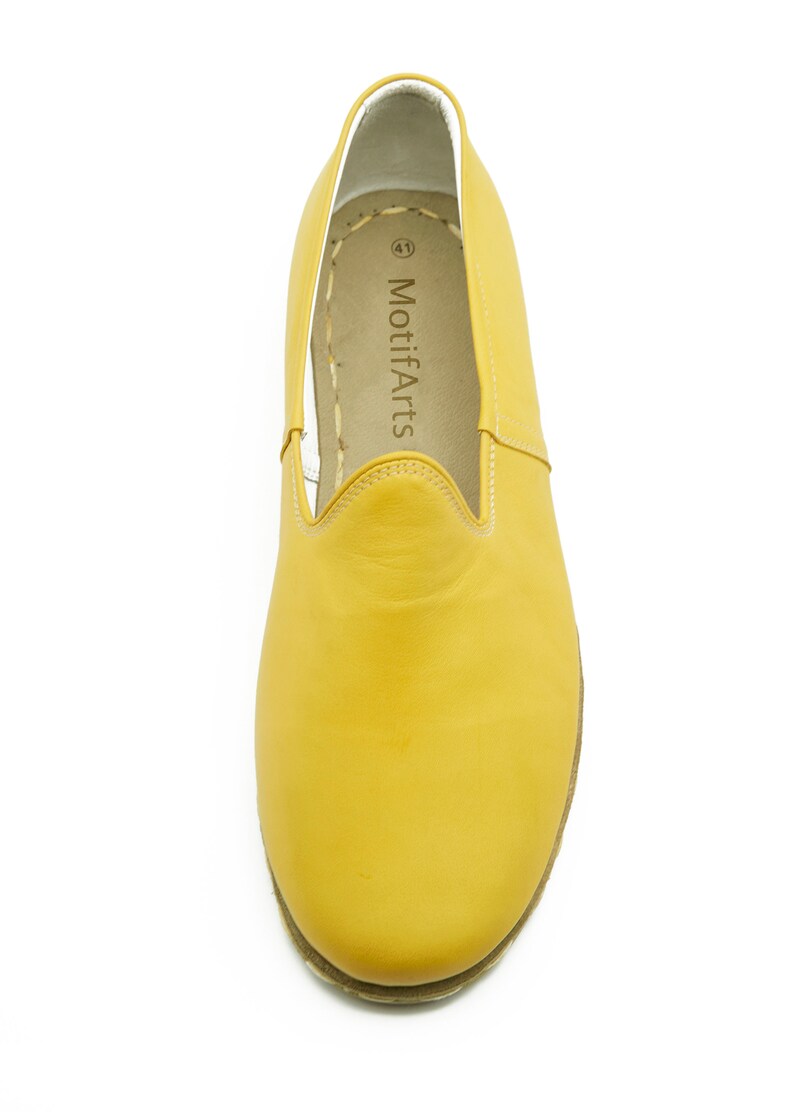 Puede incluir: Un par de zapatos de cuero amarillo de vestir sin cordones con interior blanco y el texto "MotifArts" impreso en la plantilla.
