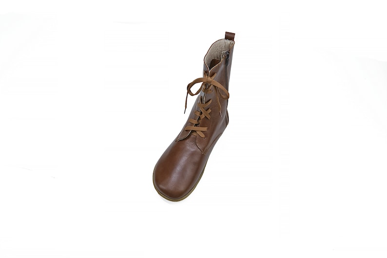 May include: Brown leather ankle boots with laces. The laces are a lighter brown color. The boots have a rounded toe.