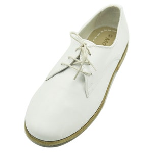 Puede incluir: Zapatos de cuero blanco con cordones y suela marr&oacute;n. Los zapatos tienen un dise&ntilde;o sencillo y est&aacute;n hechos de cuero de alta calidad.
