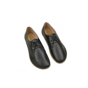 May include: A pair of black leather lace-up shoes with a rounded toe and a low heel.
