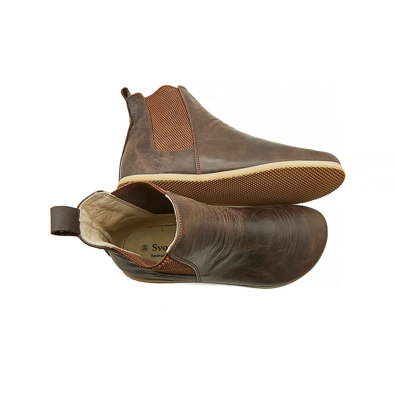 Puede incluir: Botas de tobillo de cuero marr&oacute;n con un dise&ntilde;o de f&aacute;cil calce y suela de goma. Las botas tienen una textura similar al ante y una punta ligeramente puntiaguda.