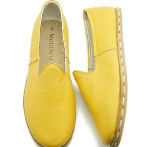 Puede incluir: Un par de zapatos de cuero amarillo de vestir sin cordones con detalles de costura blanca alrededor de la suela. Los zapatos tienen un dise&ntilde;o sencillo y est&aacute;n hechos de cuero suave. El nombre de la marca "MotifArts" est&aacute; impreso en el interior del zapato.