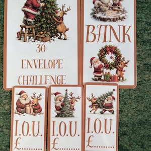 May include: A set of five rectangular cards featuring Christmas illustrations of Santa Claus and a reindeer. The largest card reads 30 ENVELOPE CHALLENGE, another reads BANK, and three smaller cards read I.O.U. with a space for a pound sterling amount.