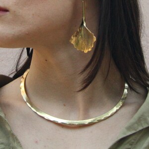 Looking for a unique necklace that channels ancient power and elegance? This handcrafted golden brass choker blends Celtic and Viking aesthetics in a sleek brutalist form. A timeless accessory for bold, modern women.