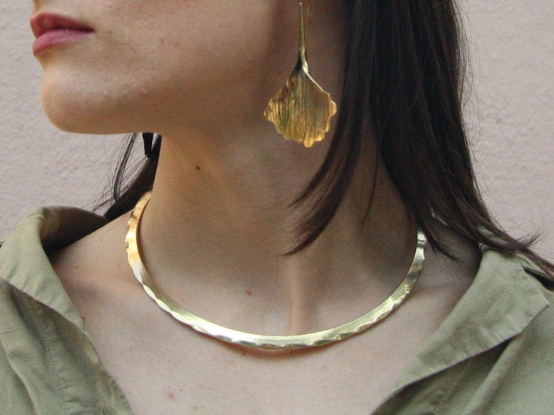 Looking for a unique necklace that channels ancient power and elegance? This handcrafted golden brass choker blends Celtic and Viking aesthetics in a sleek brutalist form. A timeless accessory for bold, modern women.