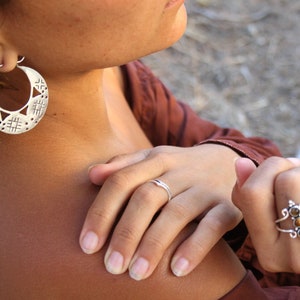 Woman wearing handmade 925 silver jewelry. Earrings with handmade openwork designs.