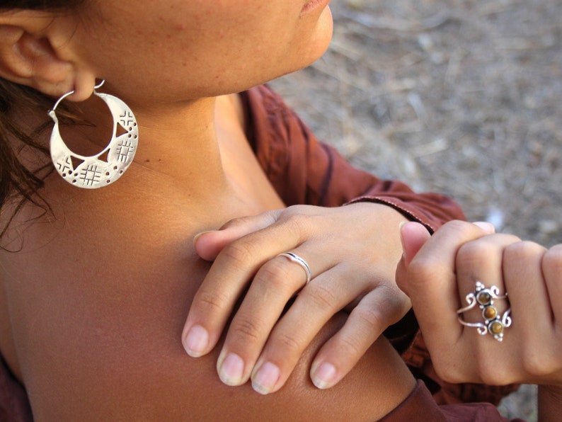 Woman wearing handmade 925 silver jewelry. Earrings with handmade openwork designs.