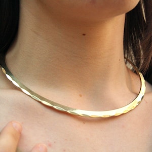 This golden brass statement choker features a rigid, open design inspired by ancient goddesses and warriors. With Celtic and Viking roots, it's ideal for anyone seeking symbolic, powerful jewelry with a bold yet elegant presence.