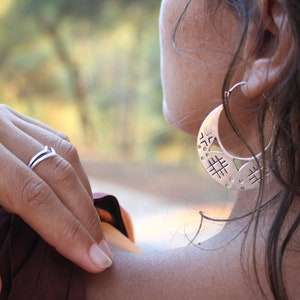 Woman wearing silver openwork earrings. Large round silver openwork tribal earrings.