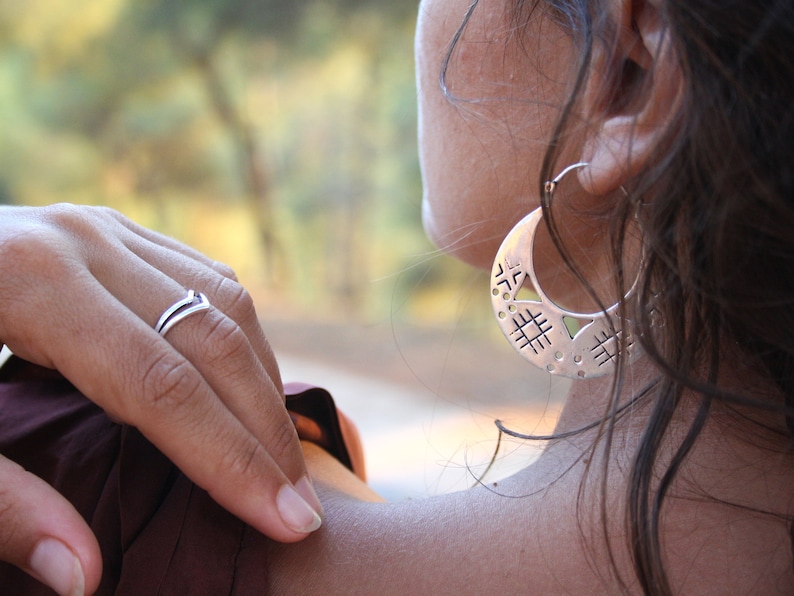 Woman wearing silver openwork earrings. Large round silver openwork tribal earrings.